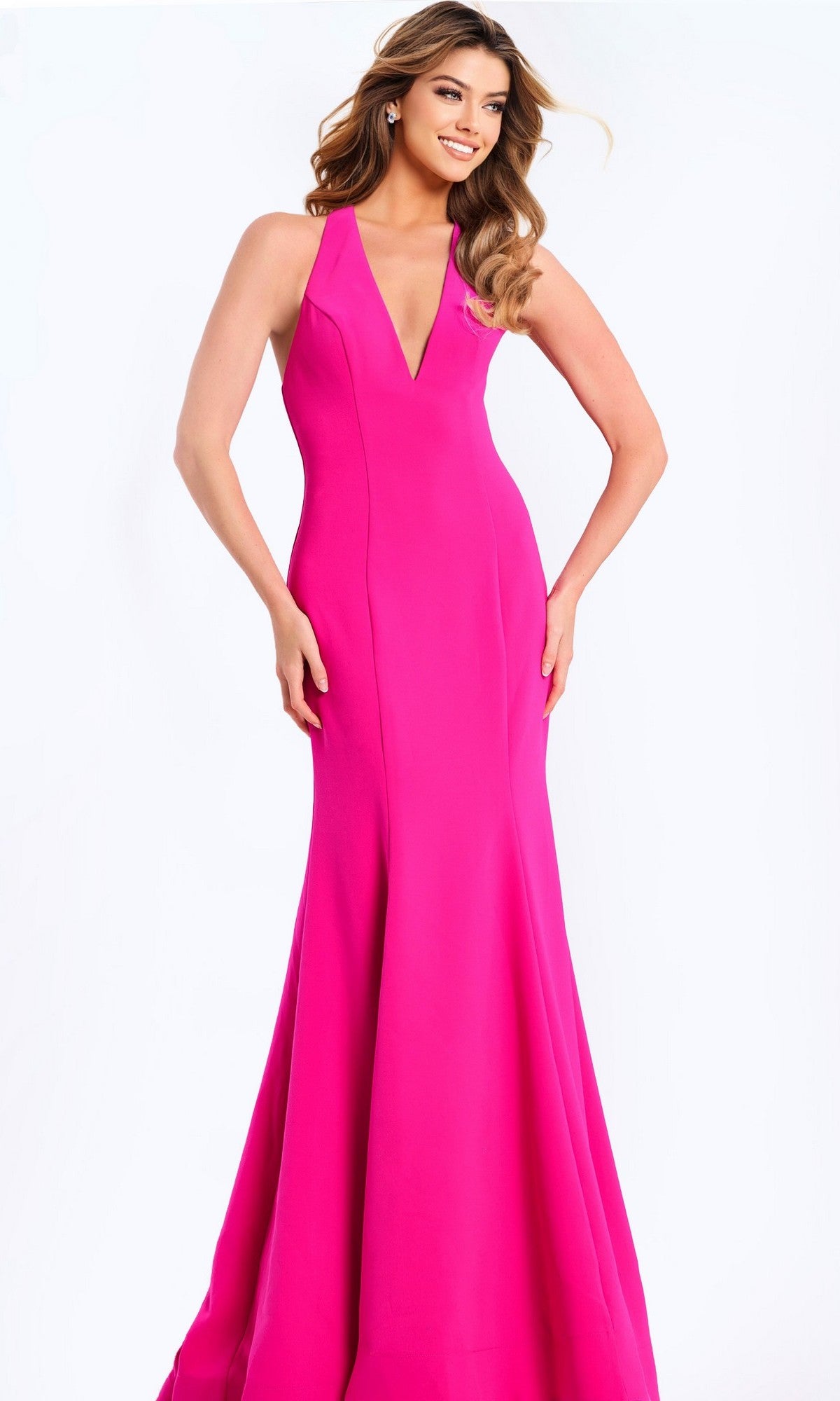 A woman stands against a white background wearing the Jovani 47639 long prom dress in fuchsia, featuring a sleeveless design, deep V neckline, and subtle mermaid silhouette.